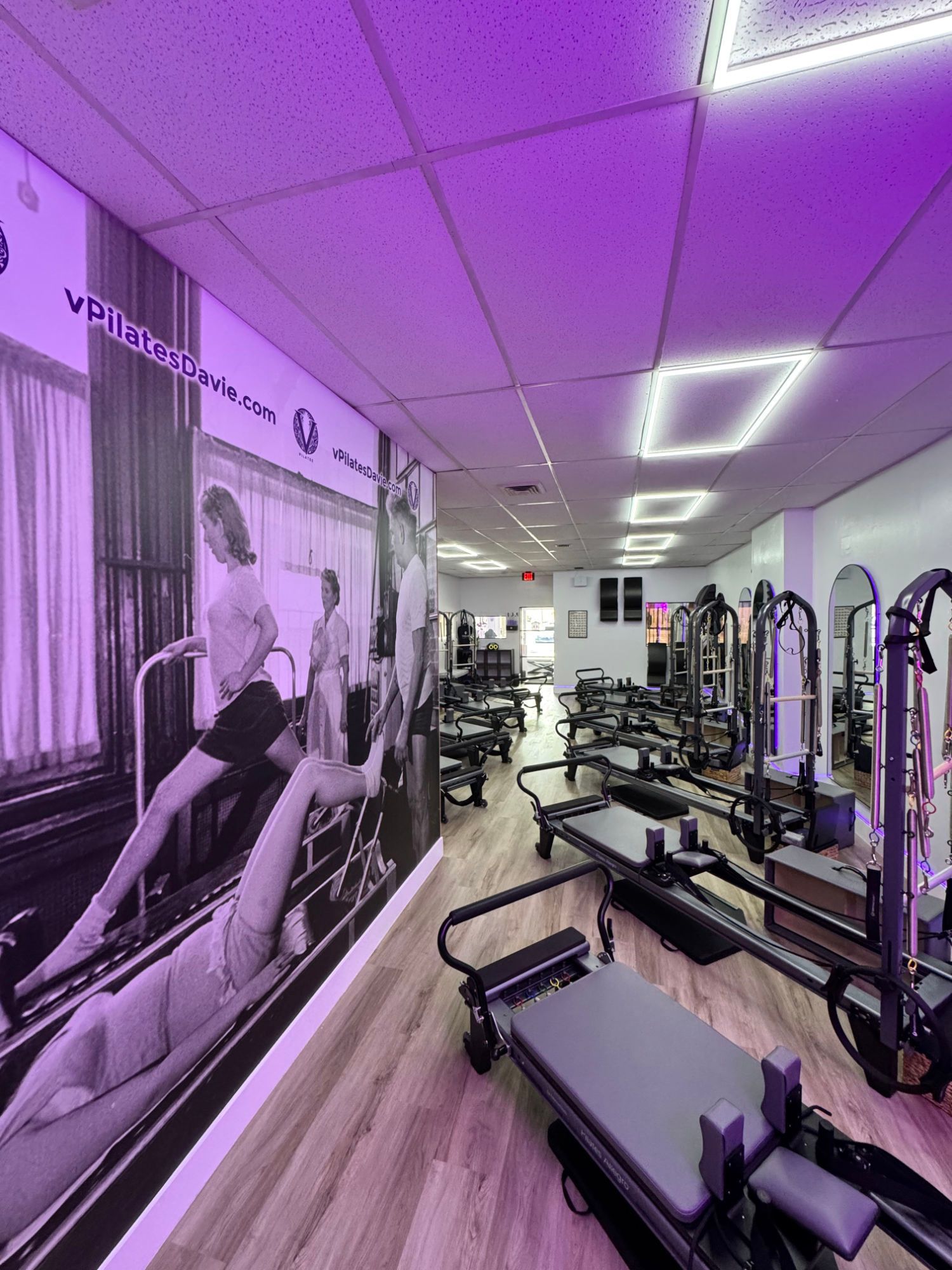 A group of people are doing exercises on pilates machines in a gym.