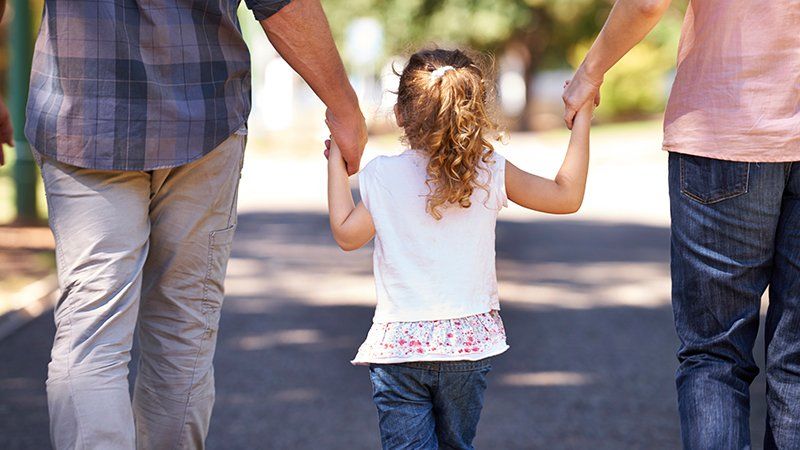Two people holding young girl's hands