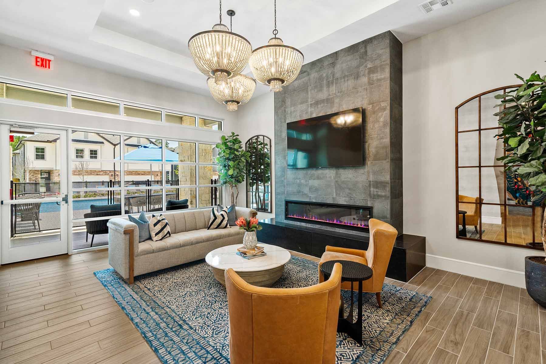 Lounge area with sofa, chairs, fireplace, large mirror, and access to outdoor patio.