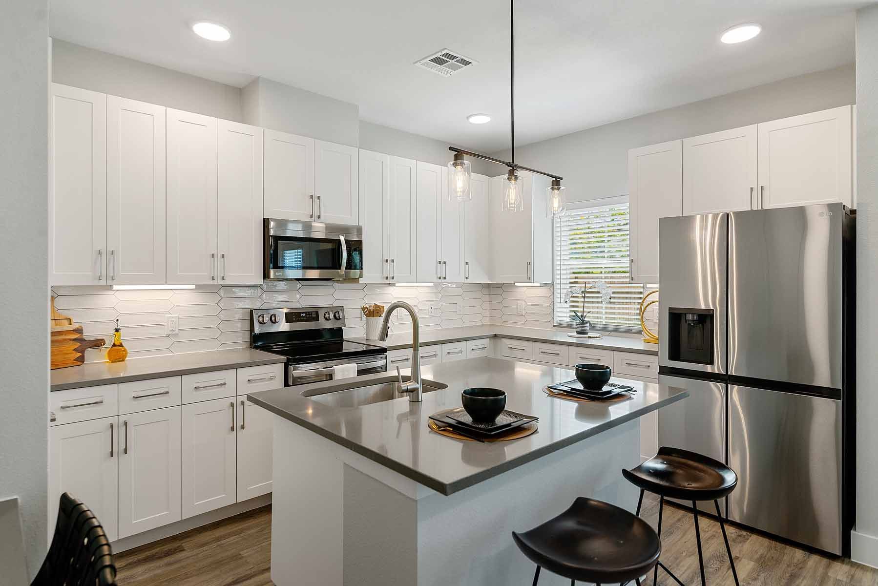 Modern kitchen with white cabinets, stainless steel appliances, and a gray island with seating.
