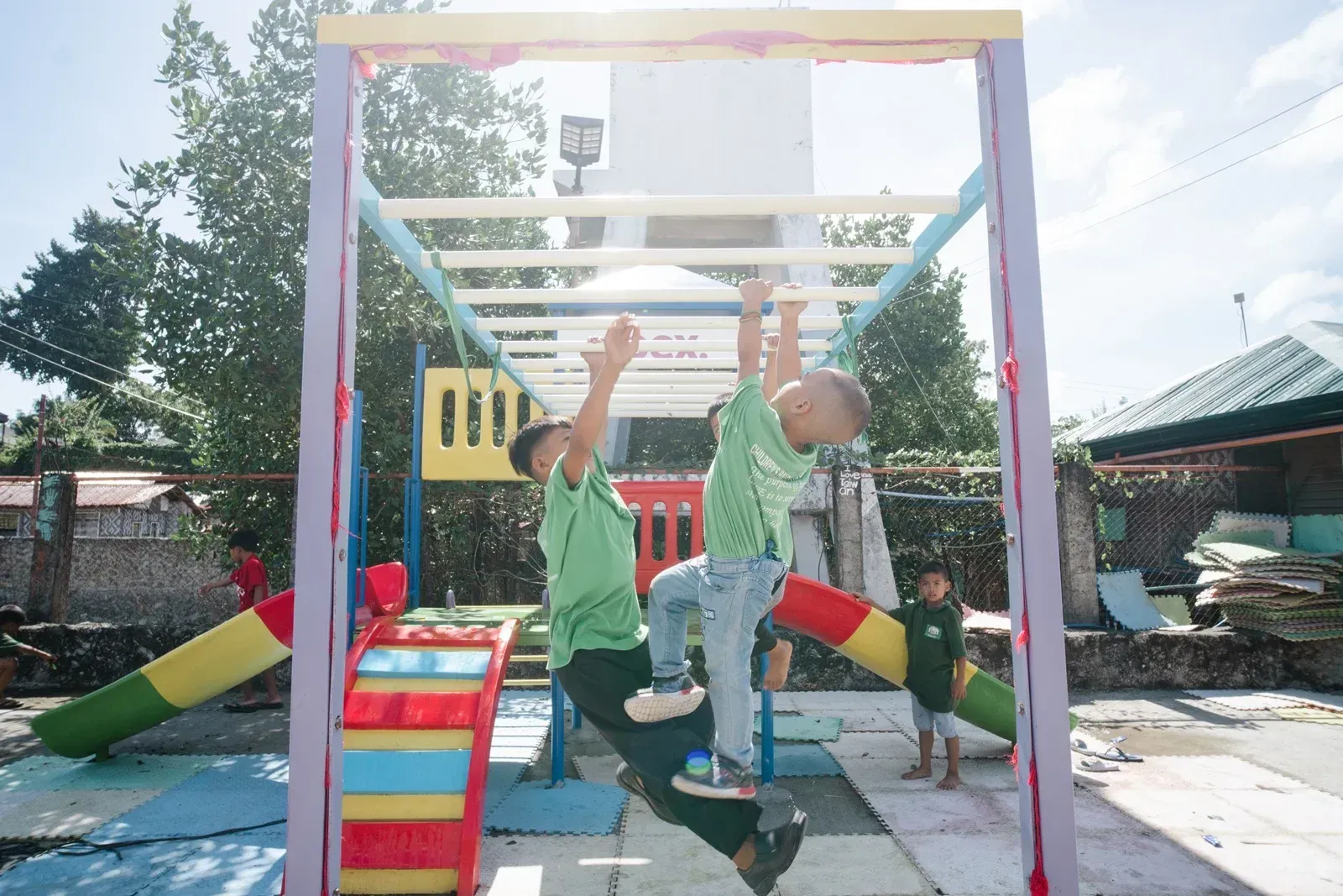 Children playing on a colorful outdoor jungle gym in a sunny playground.