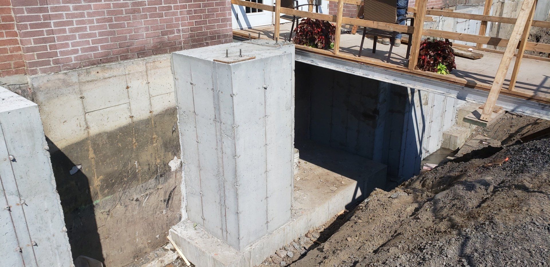 Une structure en béton est en cours de construction à côté d'un mur de briques.