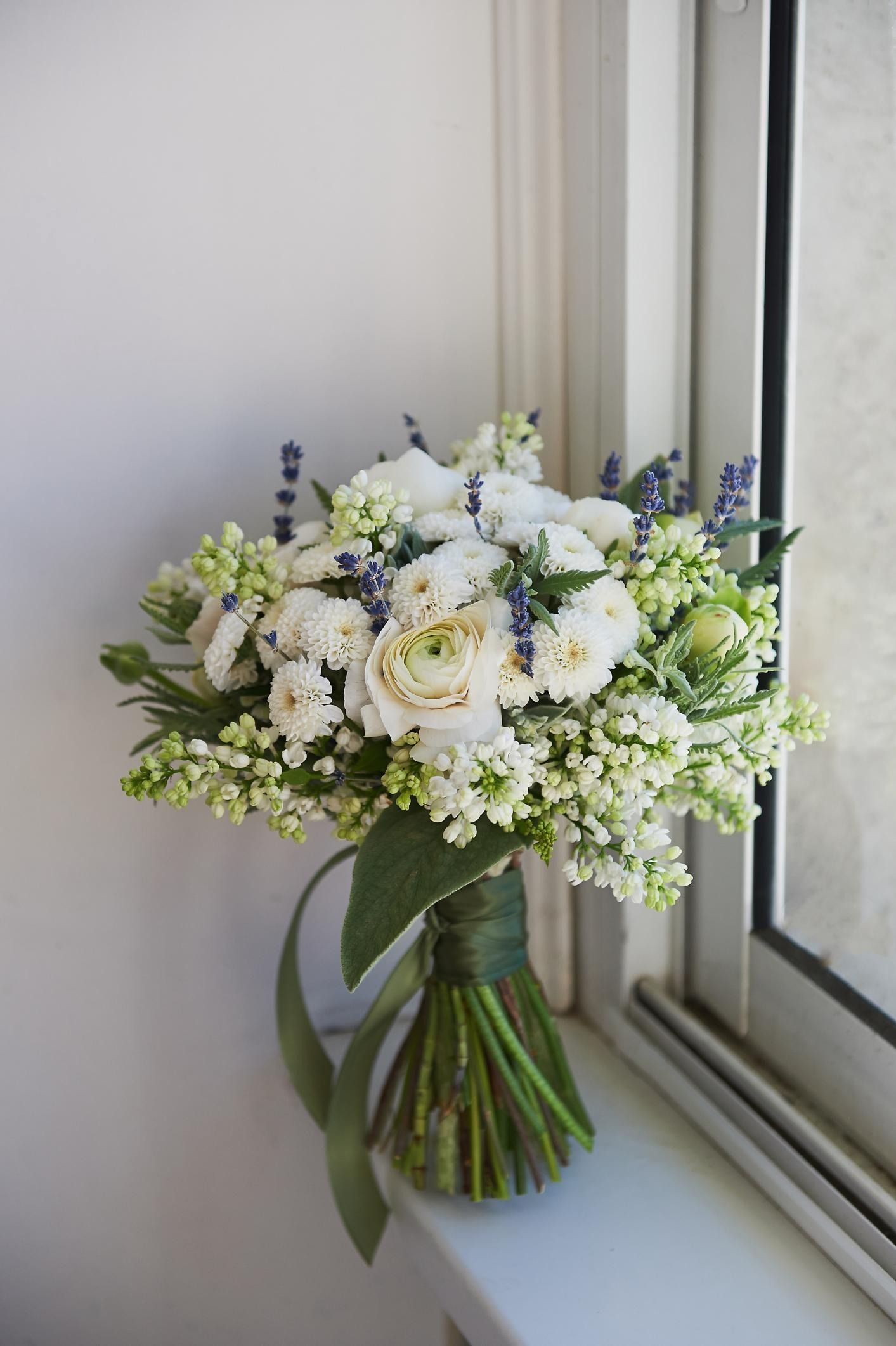 White and pale green bouquet in a glass vase by a window