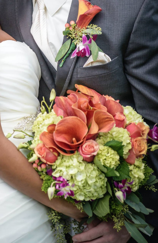 Wedding couple holding a bouquet of coral calla lilies, pink roses, and green hydrangeas