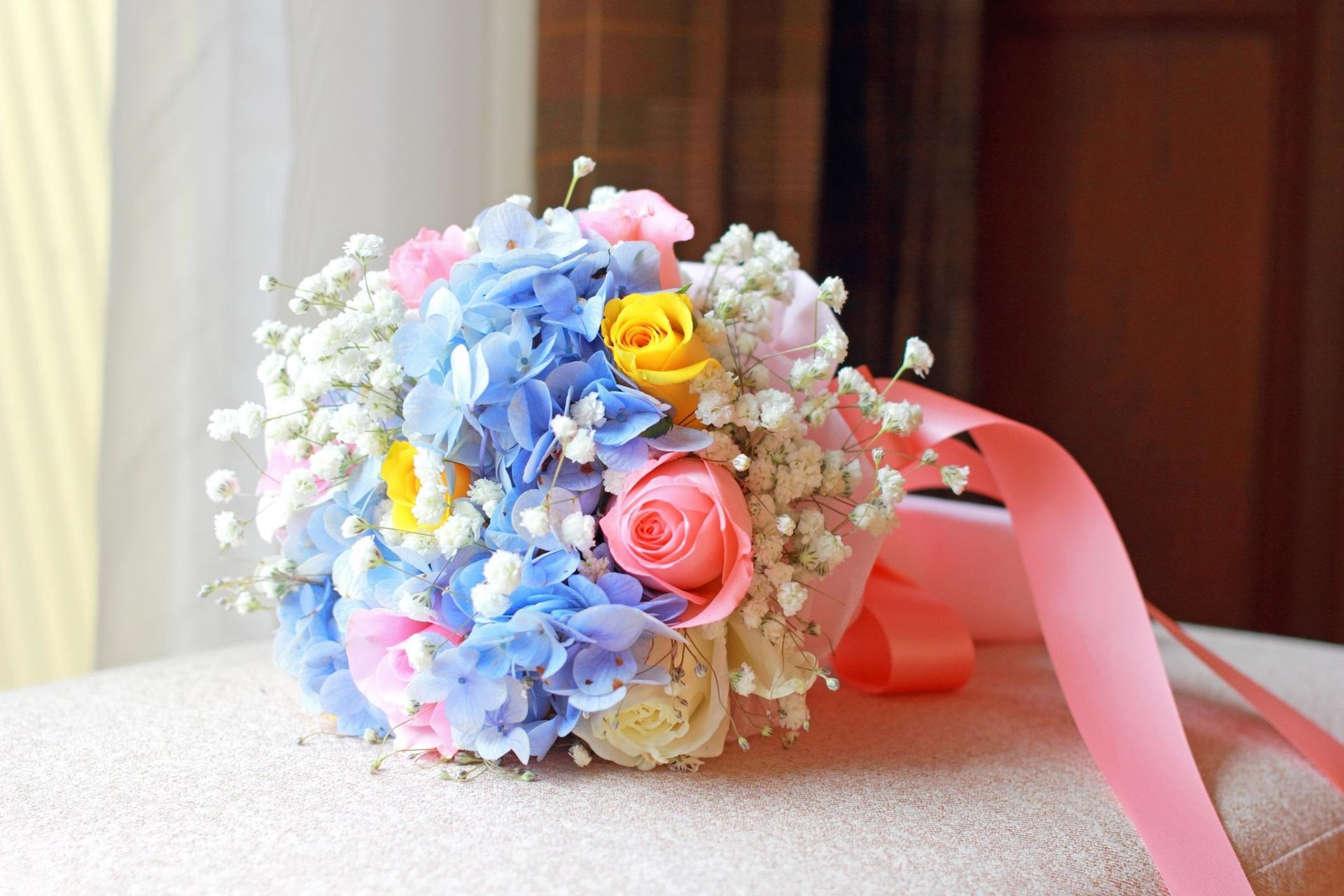 Pastel flower bouquet with pink ribbon on a table