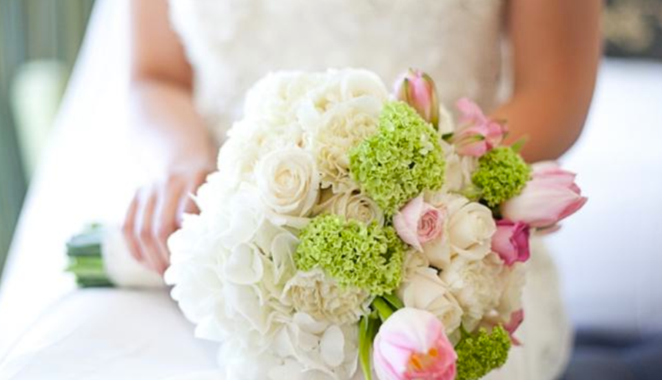 Bride holding a bouquet of white and pink roses with green flowers