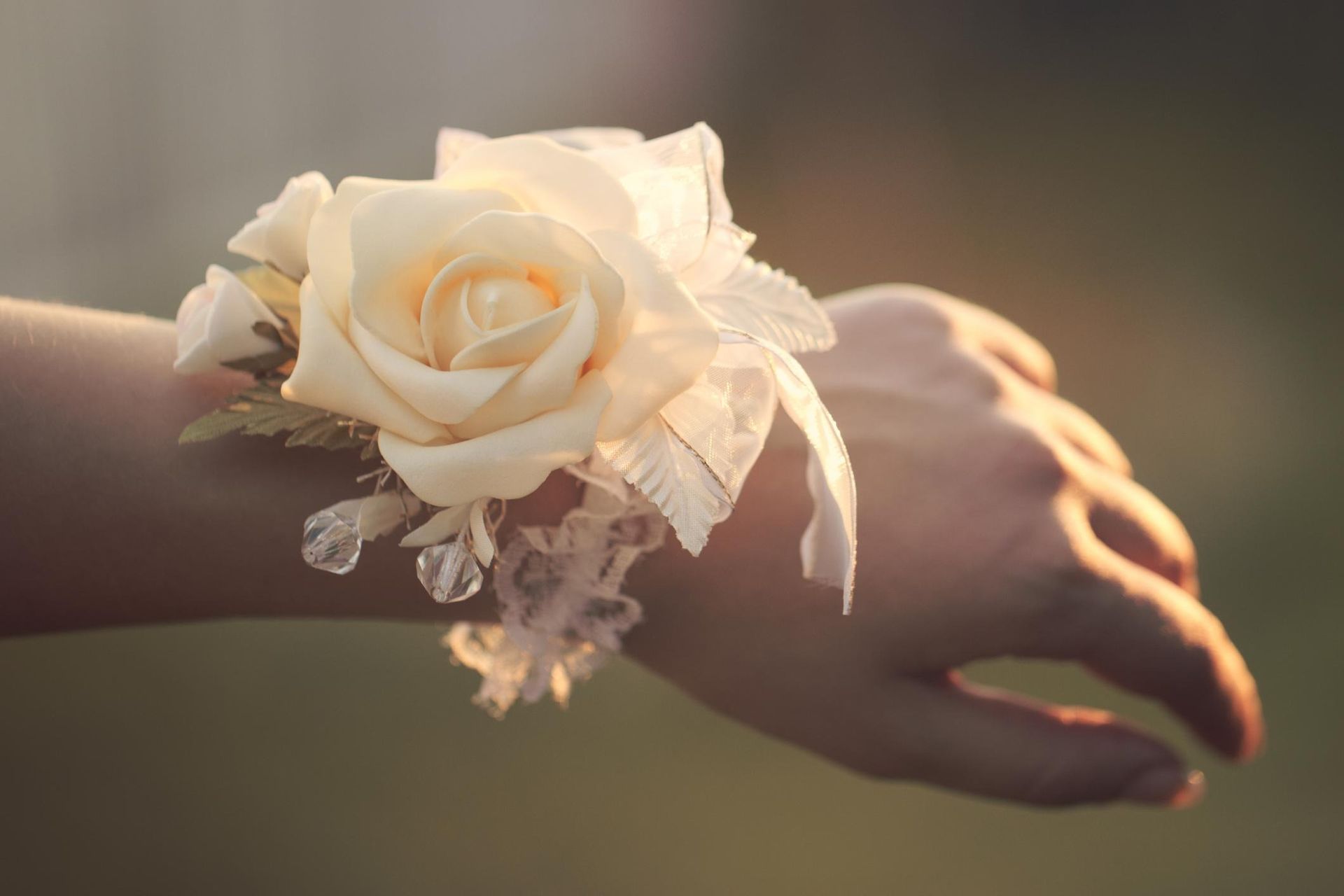 White rose corsage on a wrist with soft sunlight and blurred background