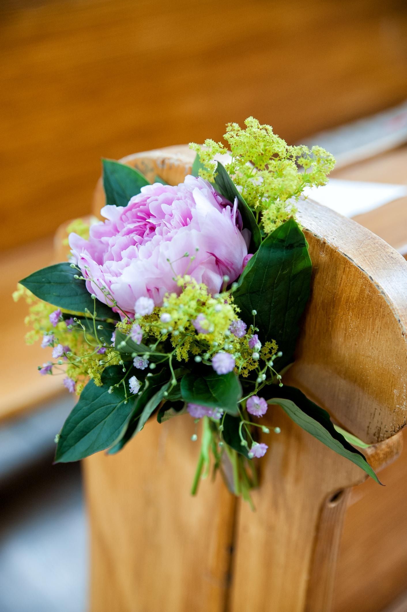 Pink and green floral arrangement on a wooden chair back