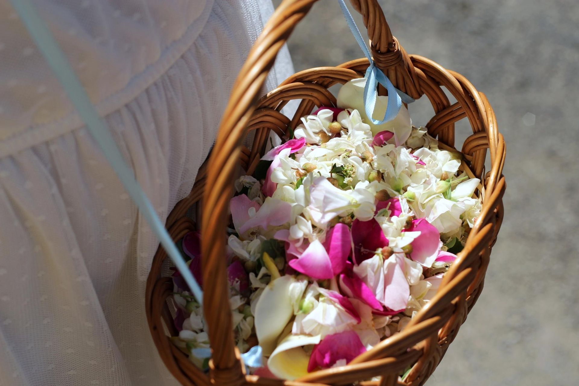 Basket of white and pink flower petals with a white ribbon
