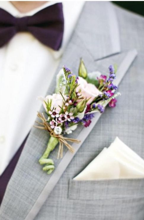 Gray suit lapel with a purple-and-white boutonniere and cream pocket square at a formal event