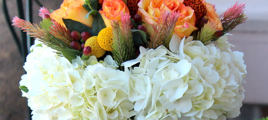 White hydrangeas with orange and pink roses in a colorful floral bouquet