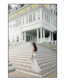Woman in a white dress standing on broad stone steps outside a grand white building