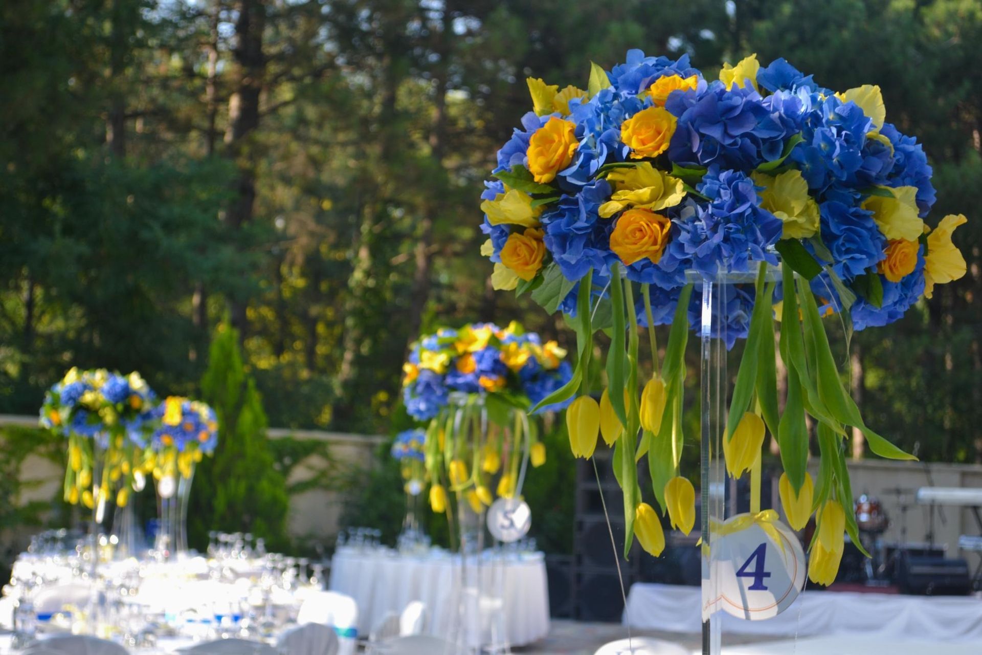 Blue and yellow floral centerpieces on a decorated outdoor banquet table