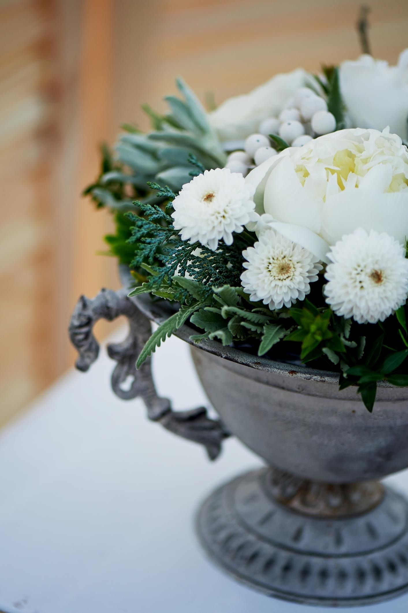 White flowers in a decorative gray metal vase on a table