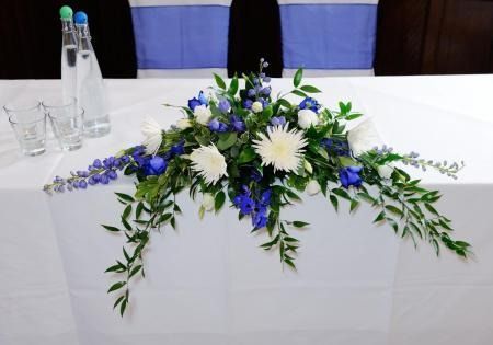 White table with blue-and-white floral centerpiece and glassware in a banquet setting
