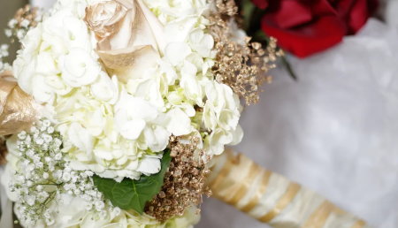 White and cream floral bouquet with red roses on a wrapped handle