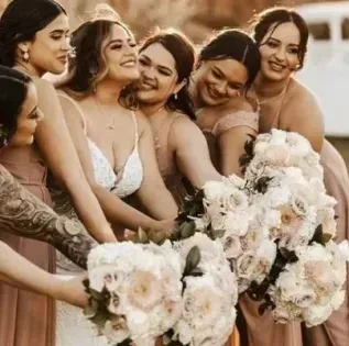 Bridesmaids in light dresses posing together with white and blush bouquets at a wedding