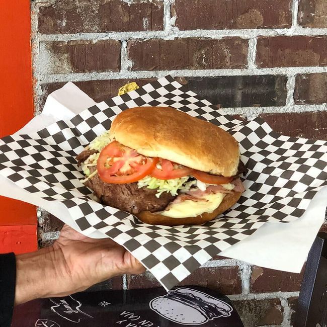 Un sándwich con tomates, cebollas y lechuga en un panecillo