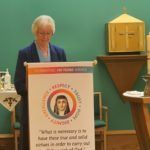 A woman is standing at a podium in a church giving a speech.