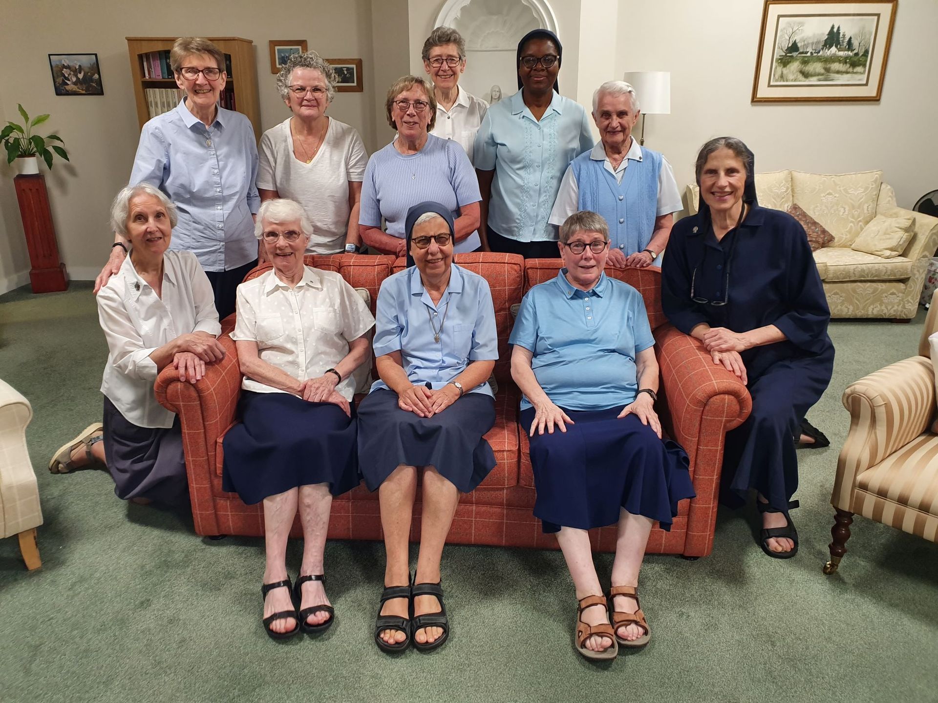 A group of older women are posing for a picture in a living room.