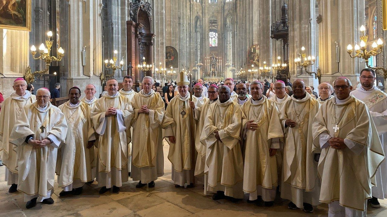 A group of priests in white robes pose inside a cathedral.