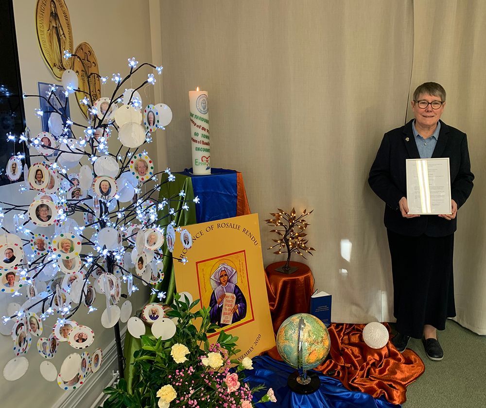 A woman is standing in front of a display with a candle and a globe