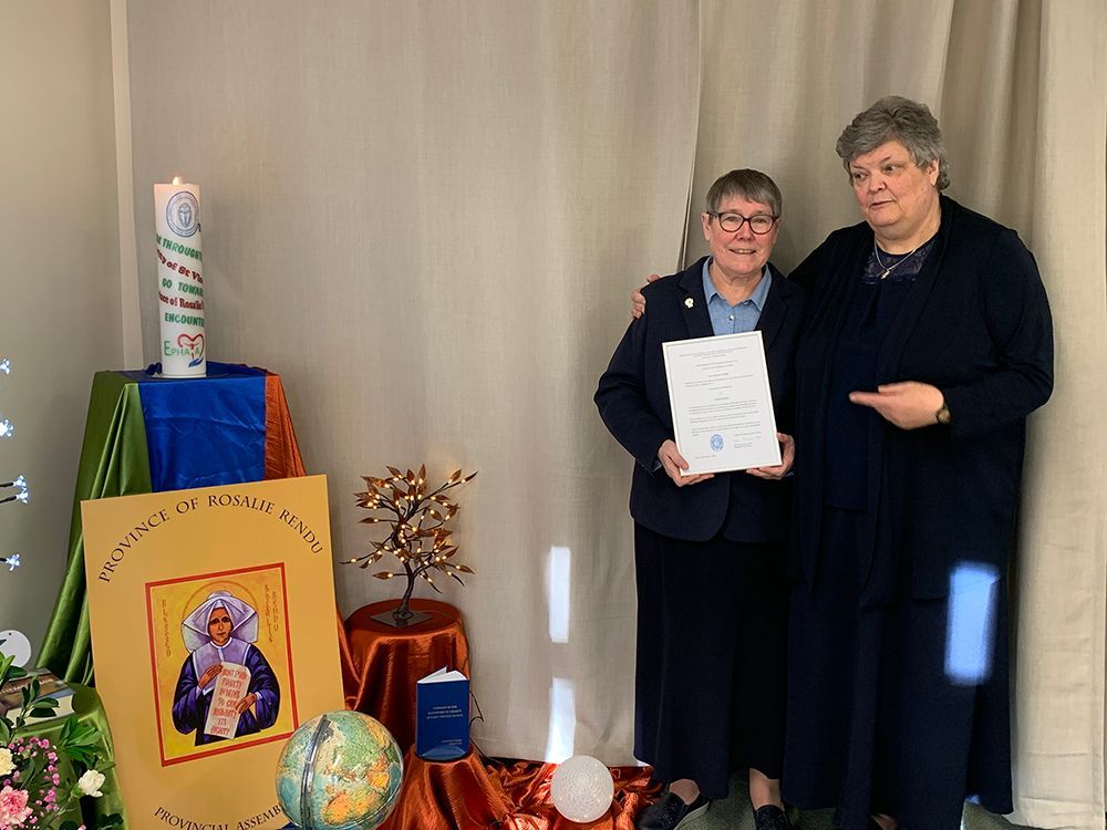 Two women are standing next to each other holding a certificate.