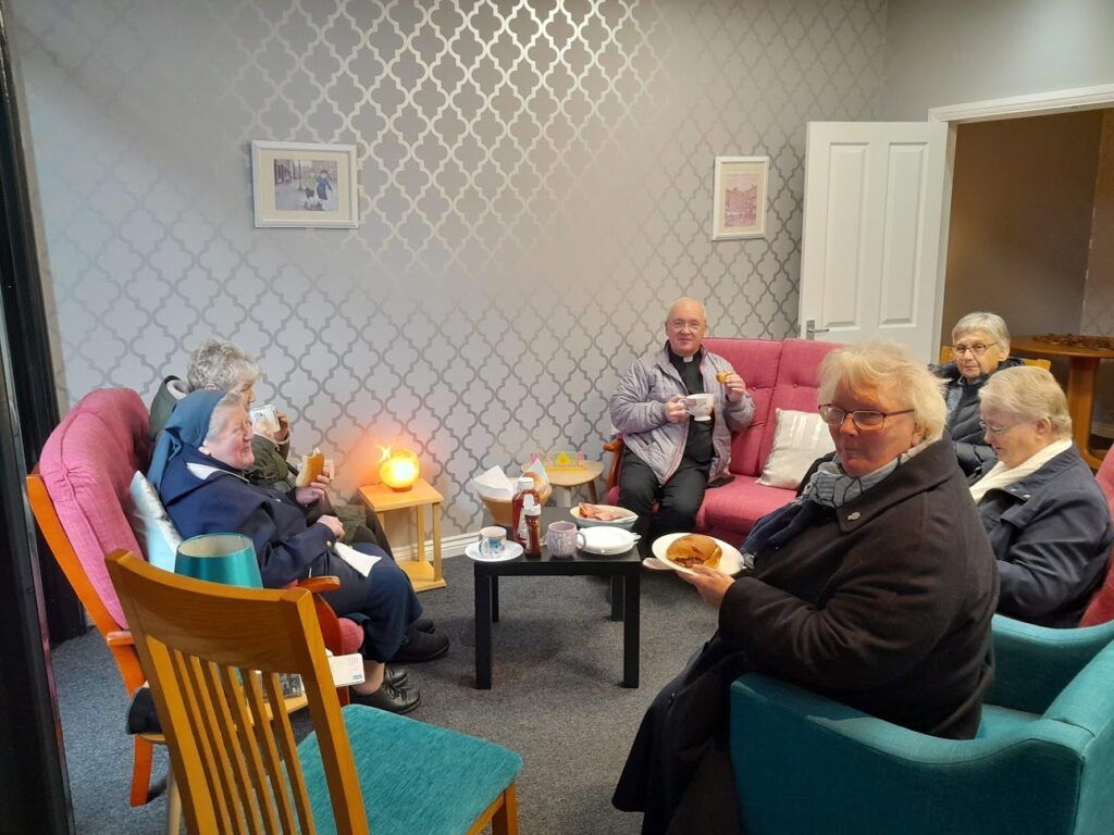 A group of people are sitting around a table in a living room.
