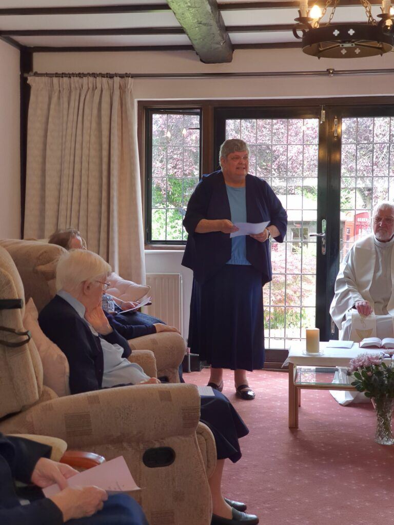A woman is standing in a living room talking to a group of people