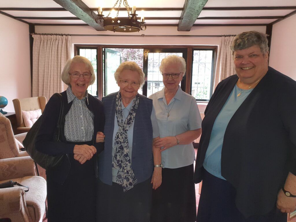 A group of older women are posing for a picture in a living room.