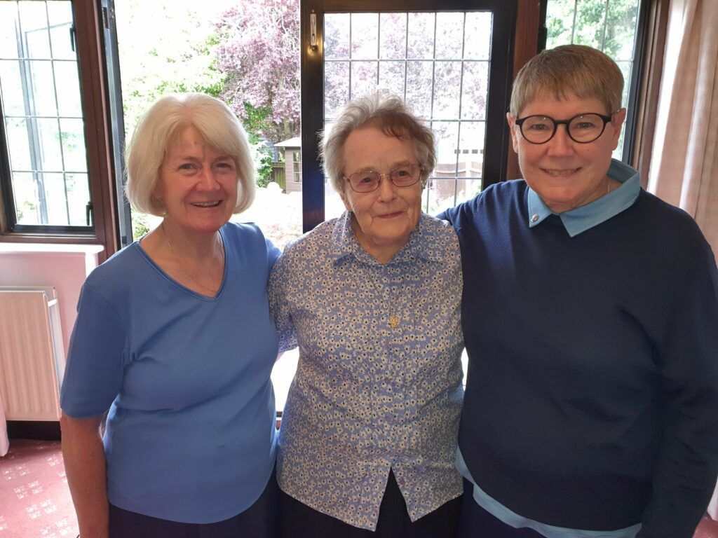Three women are posing for a picture together in a room.