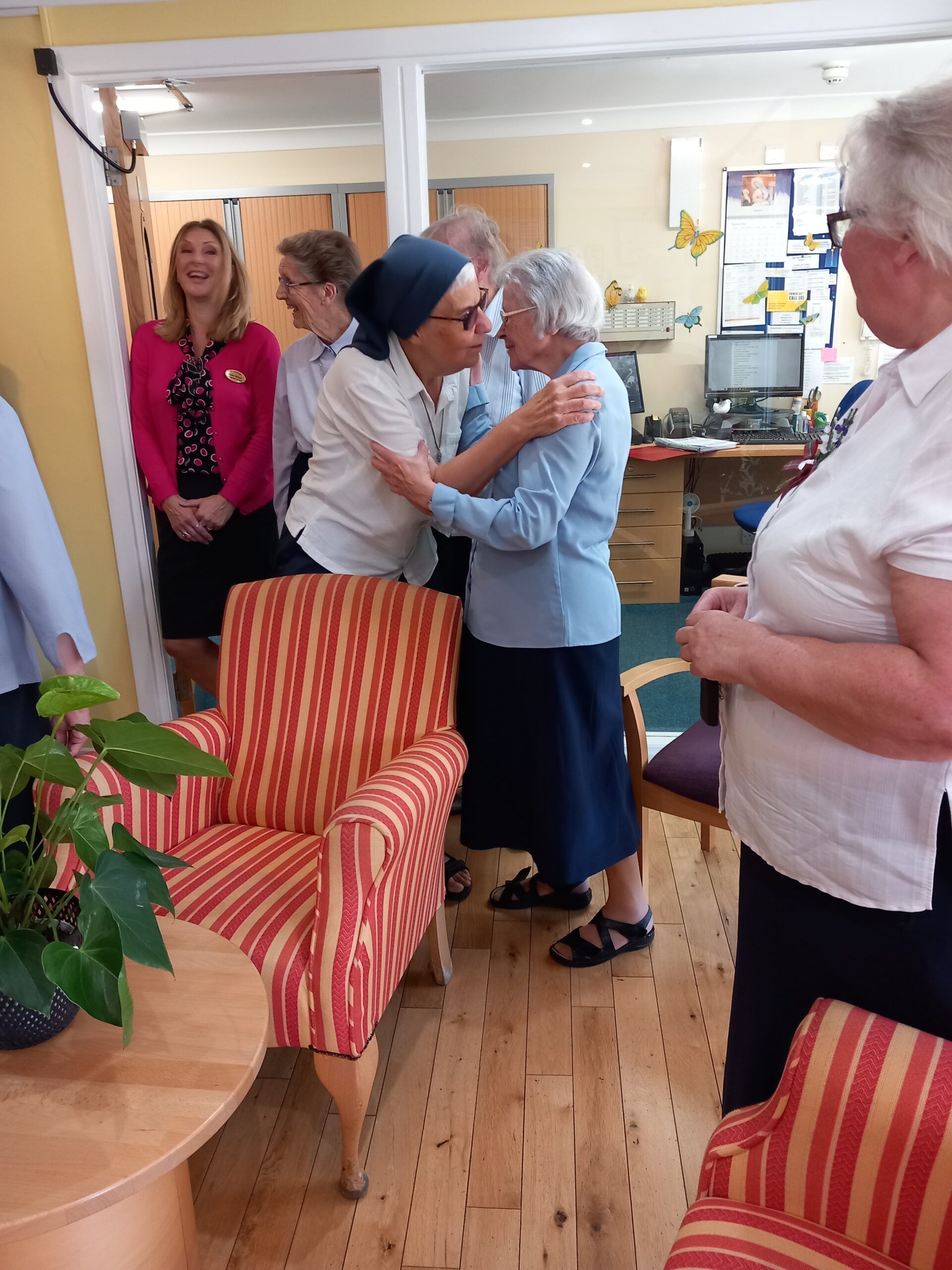 A group of women are hugging each other in a living room