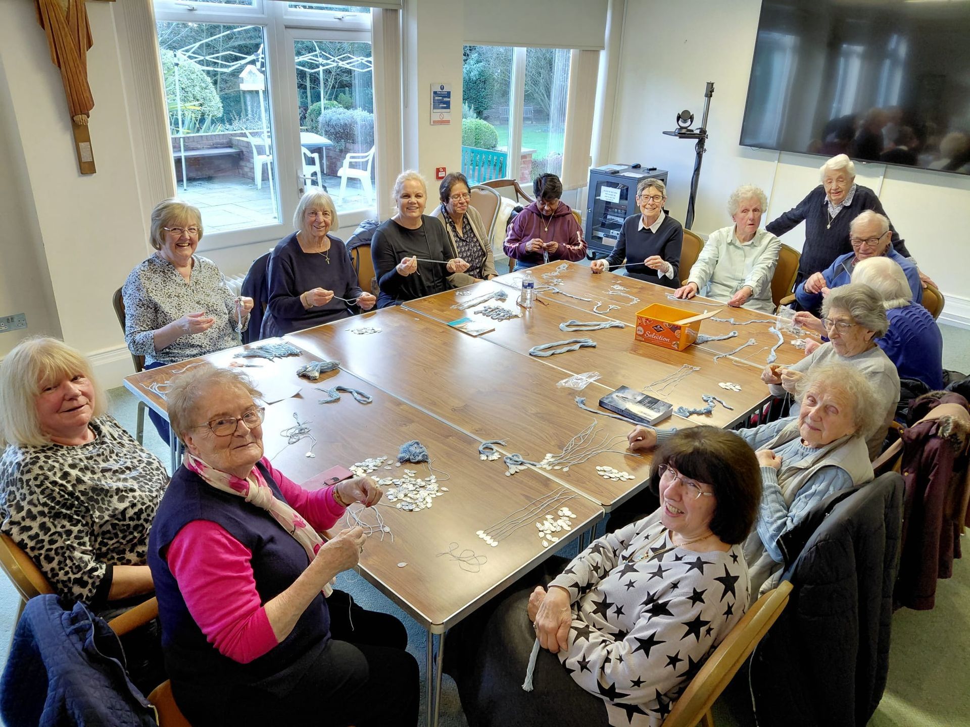 A group of people sitting around a table working on a jigsaw puzzle in a well-lit room.