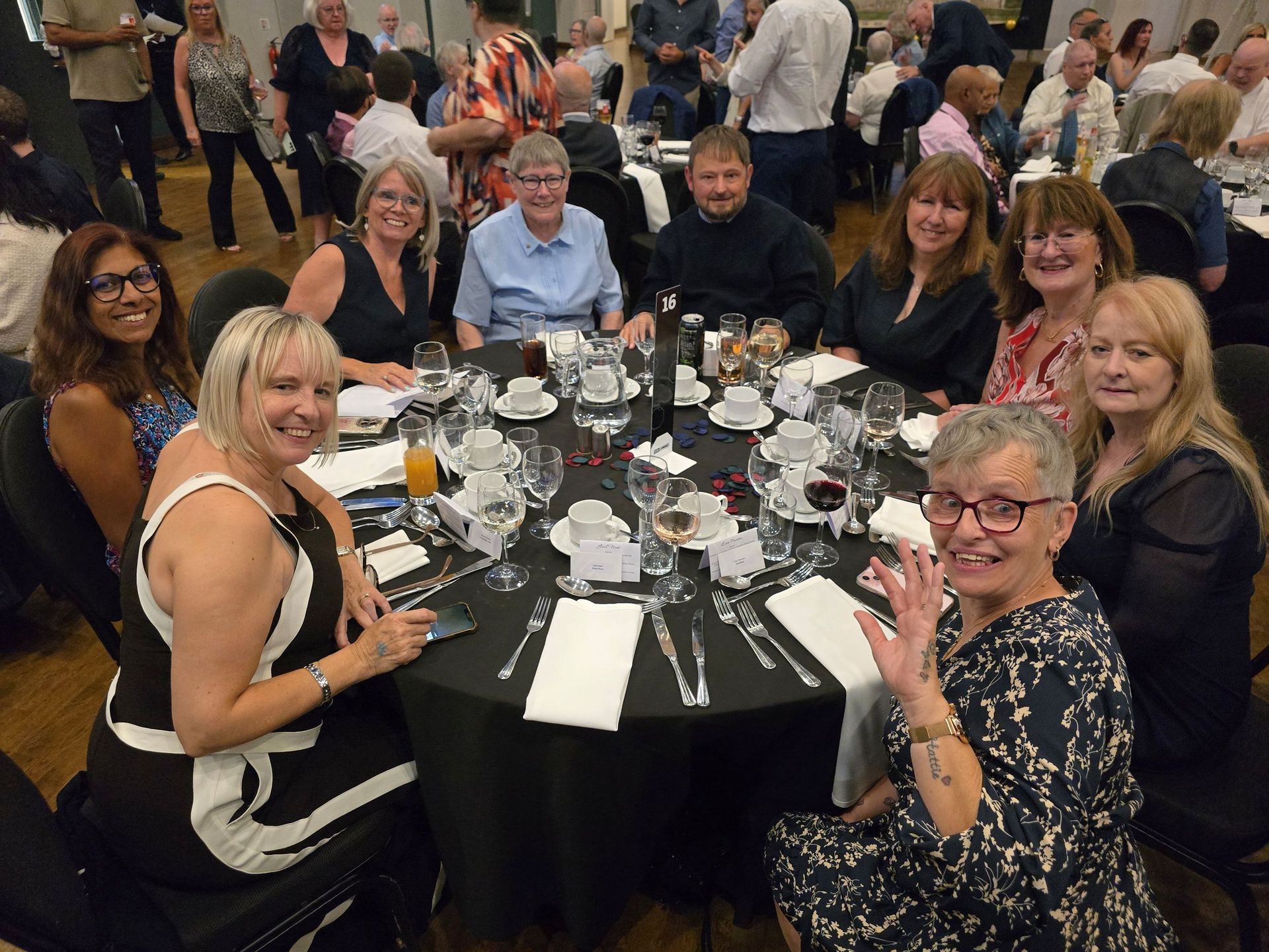 A group of people seated around a table at an event, smiling and looking at the camera.