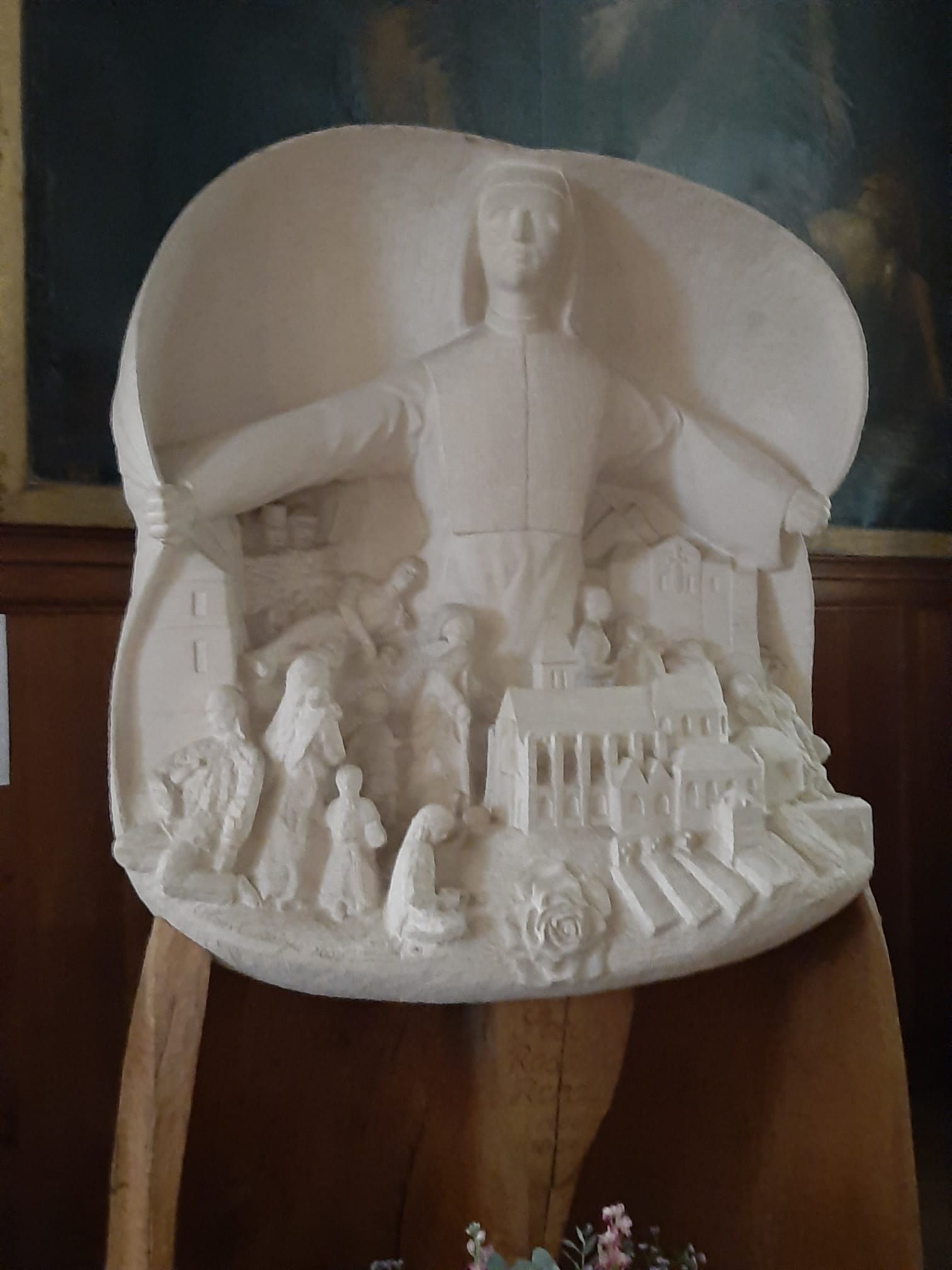 A statue of a man is sitting on a wooden stool