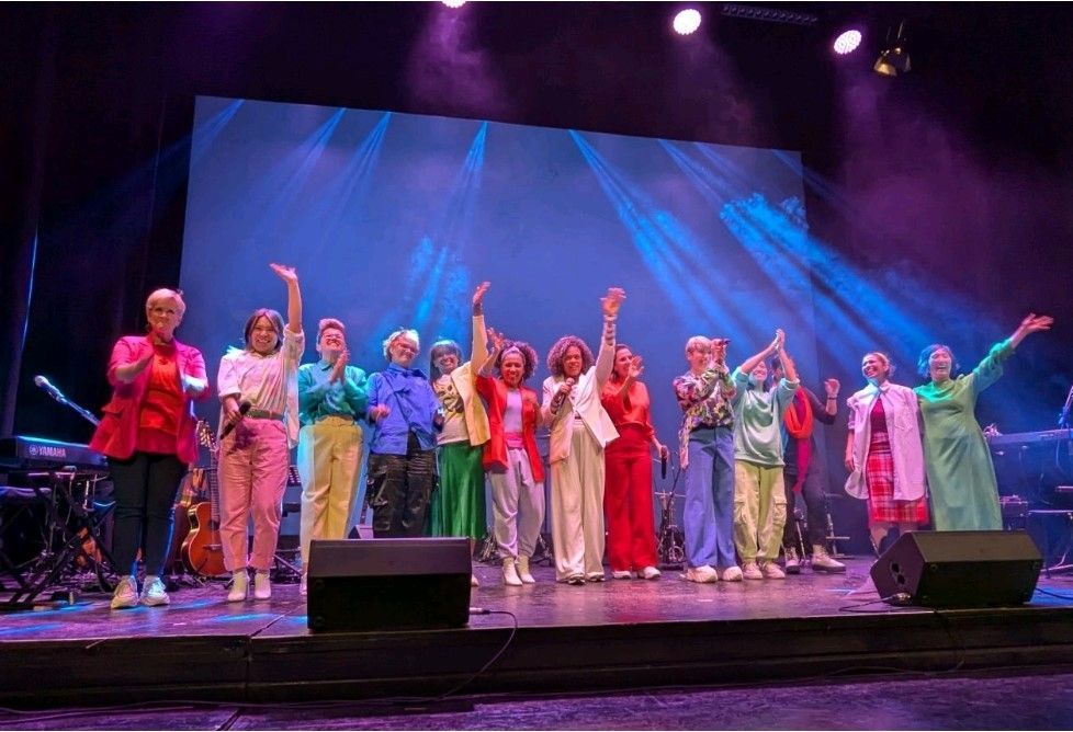 A group of people are standing on a stage with their hands in the air.