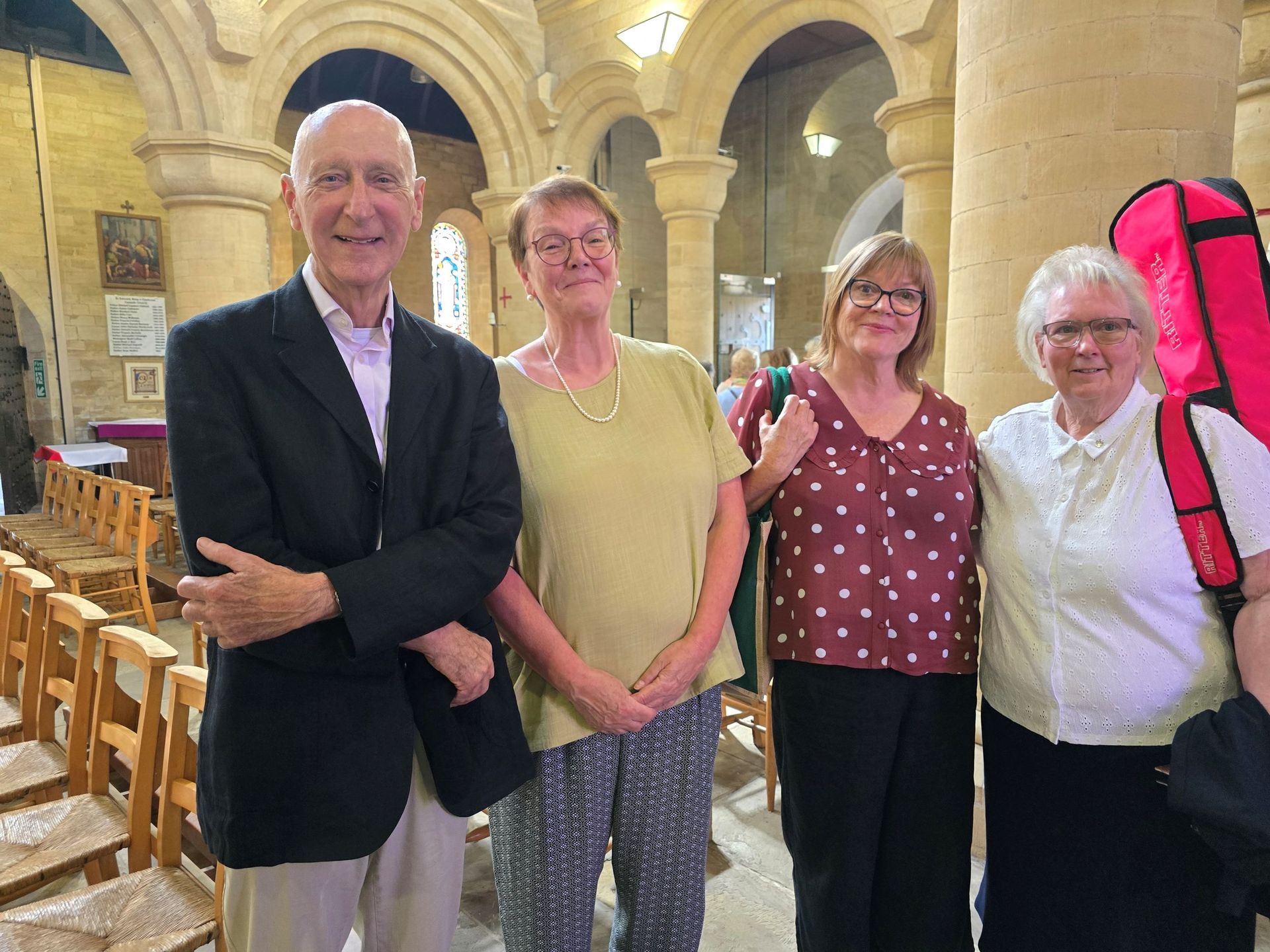Four people smiling, posing together inside a church with stone columns.