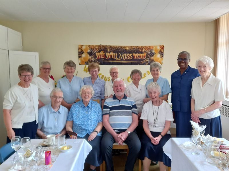 Group photo of people, many wearing white/blue, with a