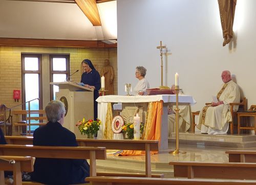 A woman is standing at a podium in a church giving a speech.