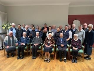 A group of elderly people are posing for a picture in a room.