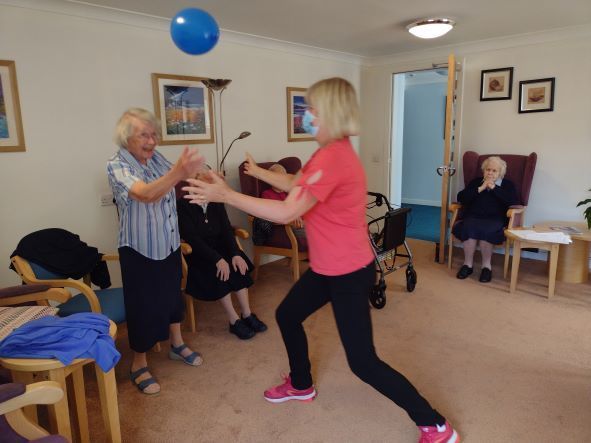 A woman in a pink shirt is playing with a blue ball
