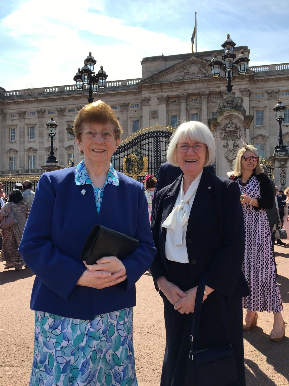 Two women are posing for a picture in front of a building