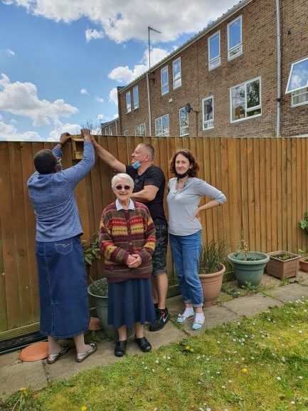 A group of people are standing in front of a wooden fence.