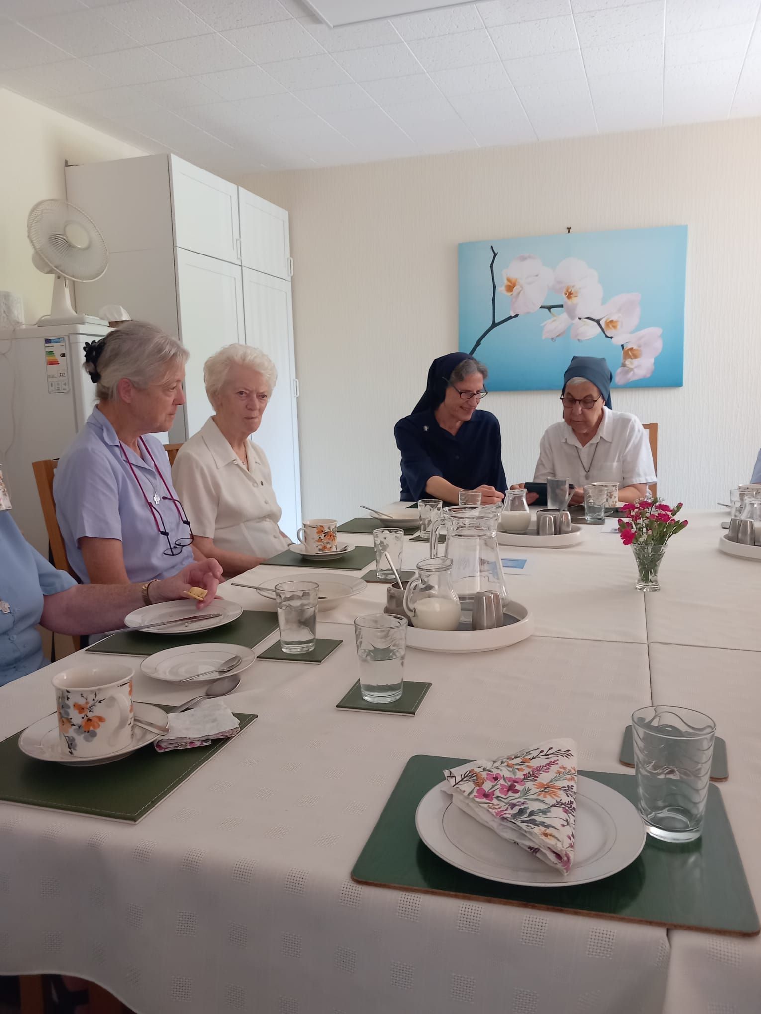 A group of people are sitting around a table with plates and cups on it.
