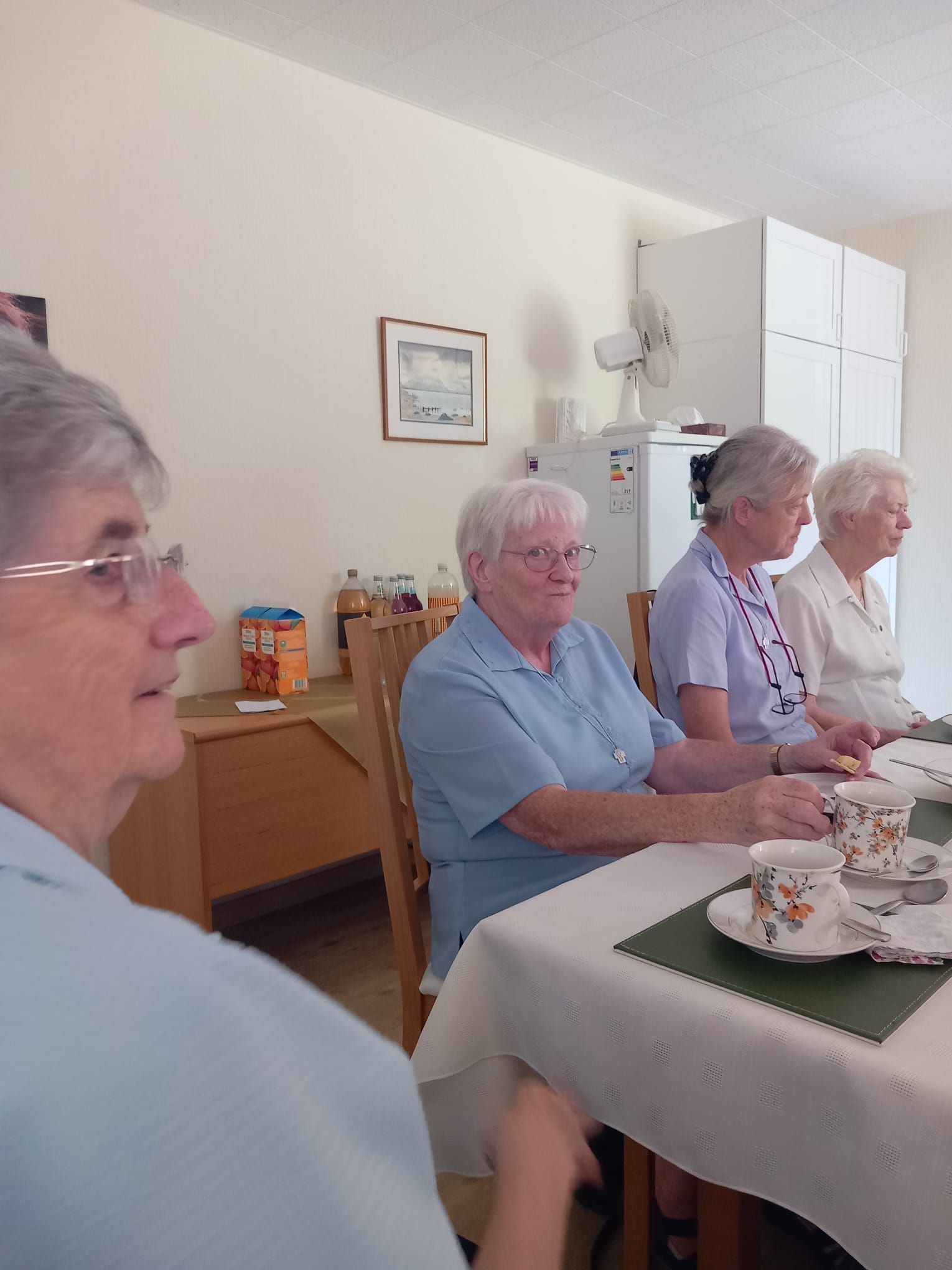 A group of women are sitting at a table with cups and saucers