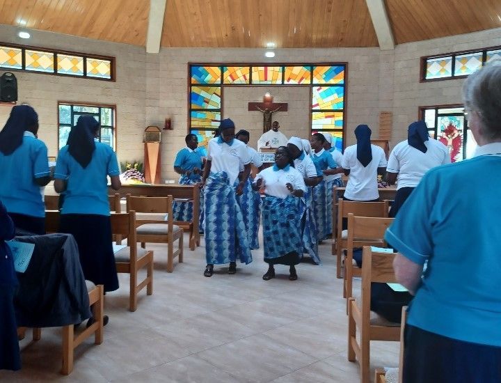 Nuns in blue outfits dance and sing during a service in a church.