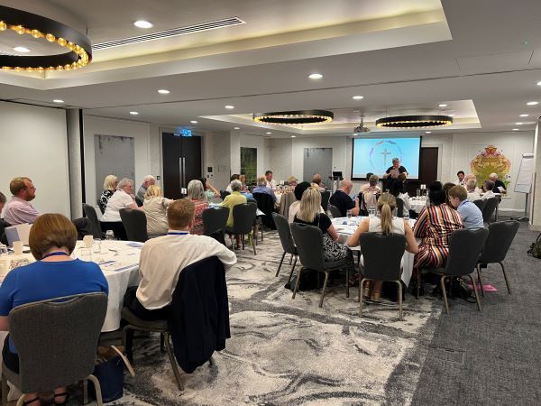 A group of people are sitting at tables in a large room.