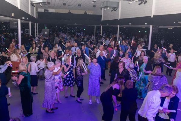 A large group of people are dancing in a large room.