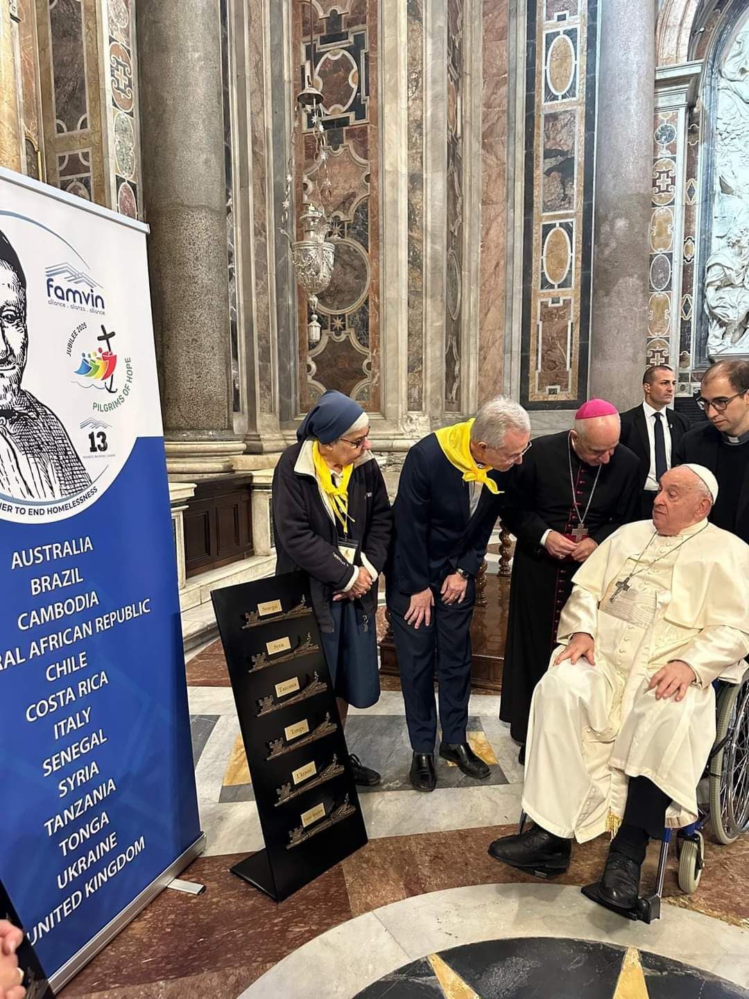 A group of people are standing around a man in a wheelchair in a church.
