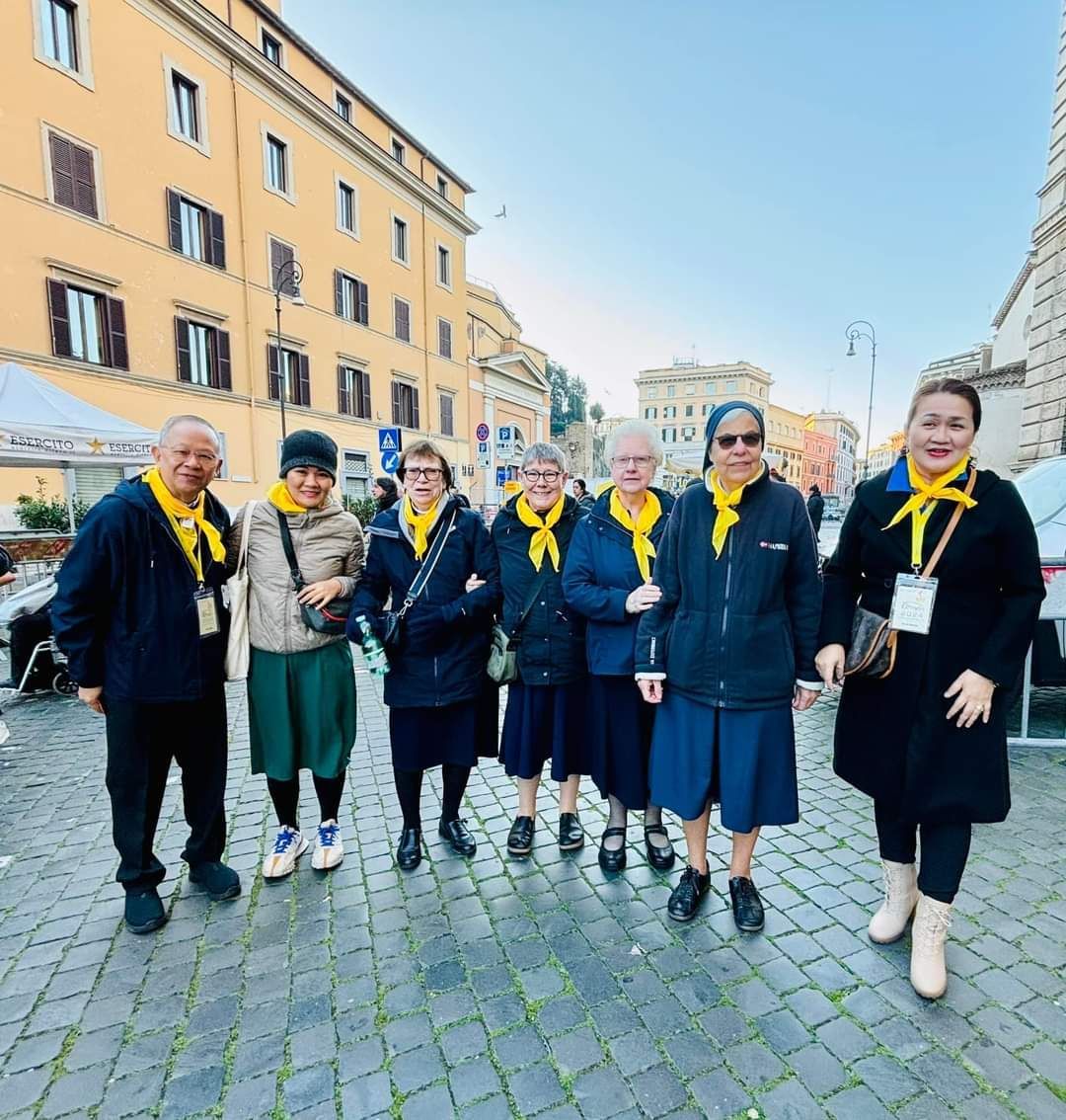 A group of people are standing on a cobblestone street in front of a building.